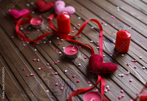 Red, pink felted hearts with red ribbon and candles on the wooden background