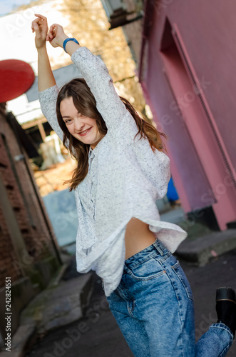 Hipster girl wearing blank white t-shirt, jeans posing against rough street wall, minimalist urban clothing style