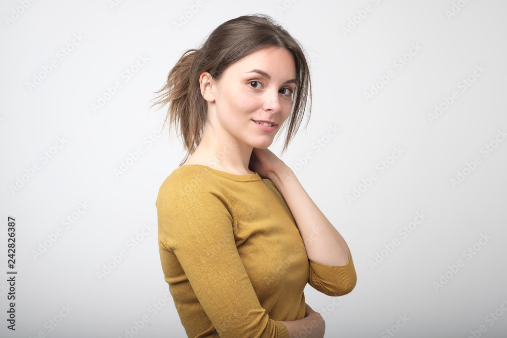 Woman smiling while looking at camera and standing against white background. Woman smiling while looking at camera and standing against white background.