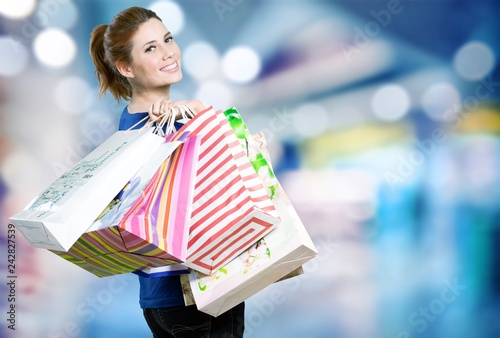 Young woman with shopping bag on background