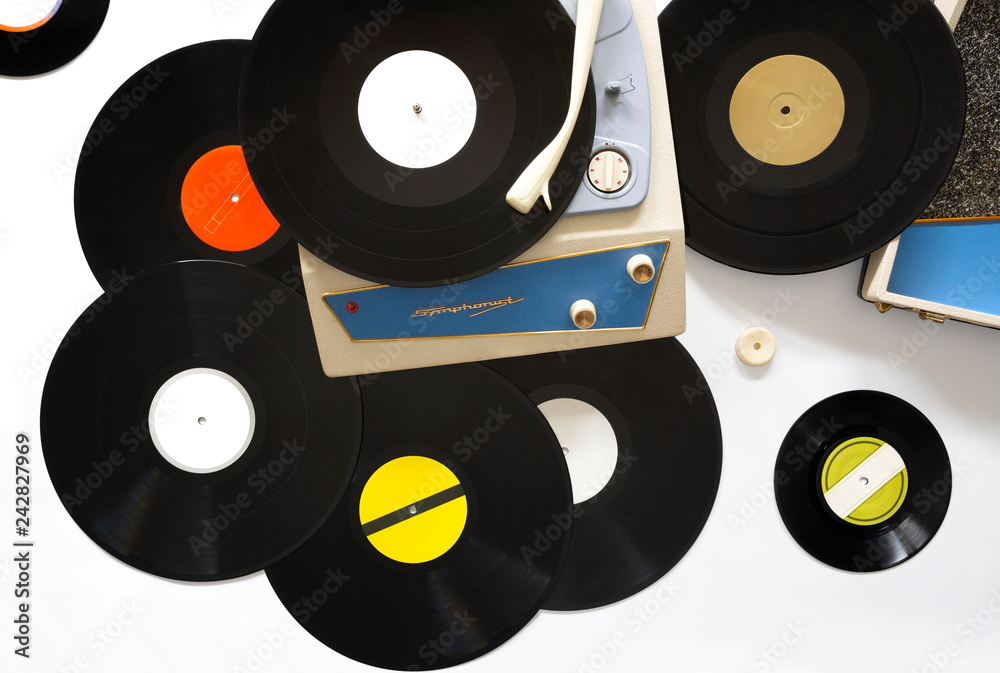 Tocadiscos portable de los años 60 y diferentes discos de vinilo colocados  sobre fondo blanco. Cocepto música. Stock Photo