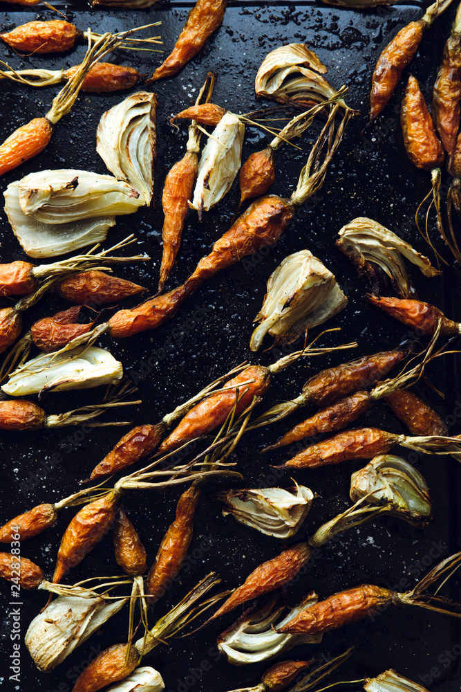 Close up. Roasted fennel and baby carrots on tray. Rustic background.
