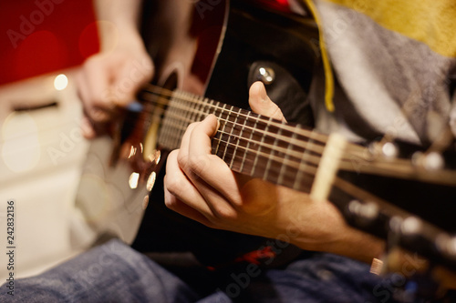 man in jeans playing guitar music at home