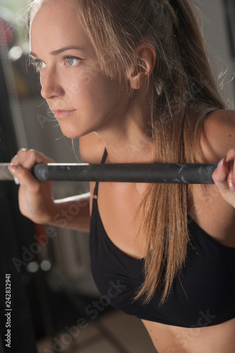 Portrait of concentrated young woman working out at the gym. Training with barbell. Fitness and sports concept.