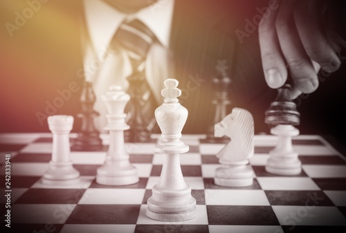 Businessman Hand Holding a Chess Piece on a Chessboard