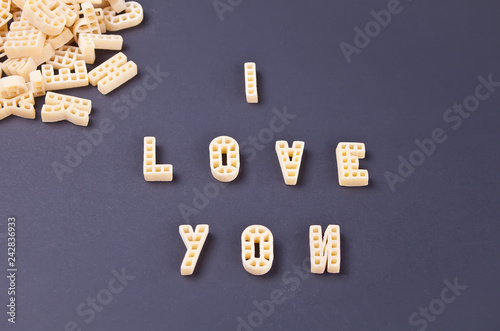 Text I love you written with macaroni in the form of letters on black wooden table background