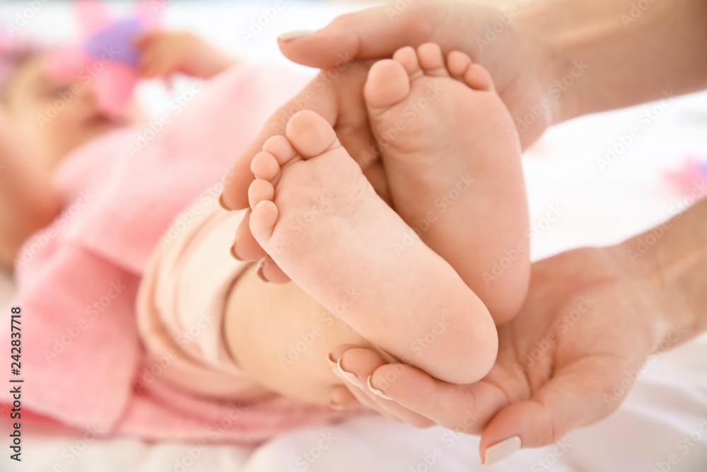 Mother's hands touching tiny feet of little baby, closeup Mother's hands touching tiny feet of little baby, closeup