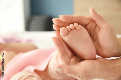 Mother's hands touching tiny foot of little baby, closeup © Pixel-Shot