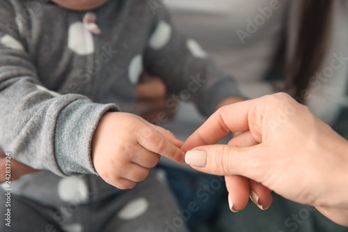 Cute baby girl touching hand of her mother  closeup