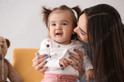 Young woman with her cute little daughter sitting in armchair