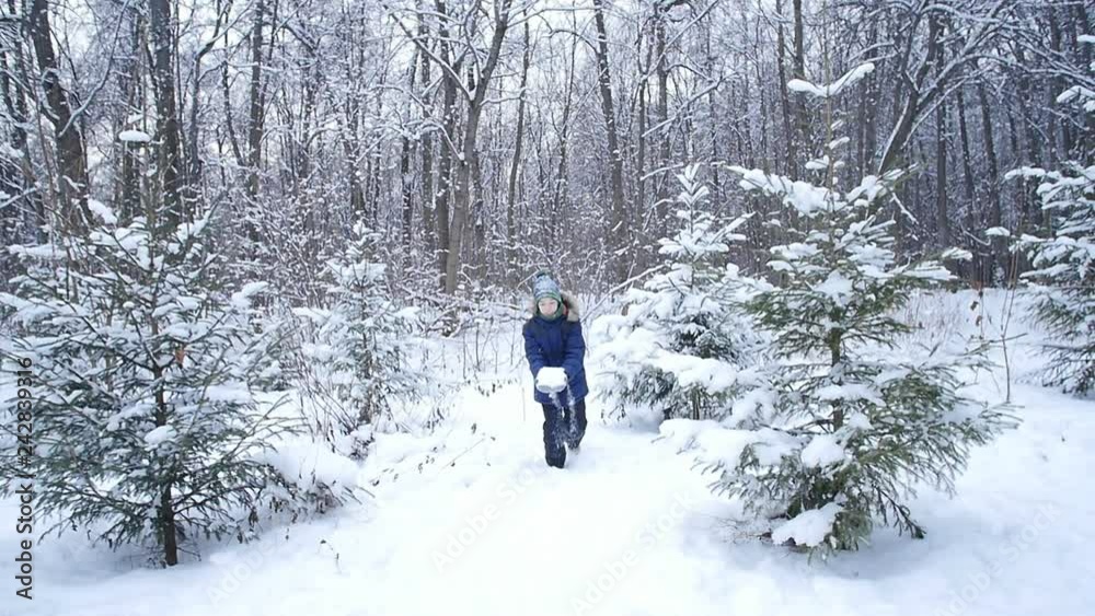 Teen boy throws snow in the winter forest. Active lifestyle, winter activity, outdoor winter games concept Teen boy throws snow in the winter forest. Active lifestyle, winter activity, outdoor winter games concept