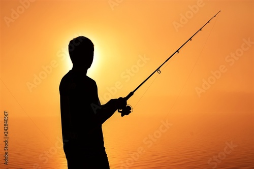 silhouette of fisherman with fishing rod and reel