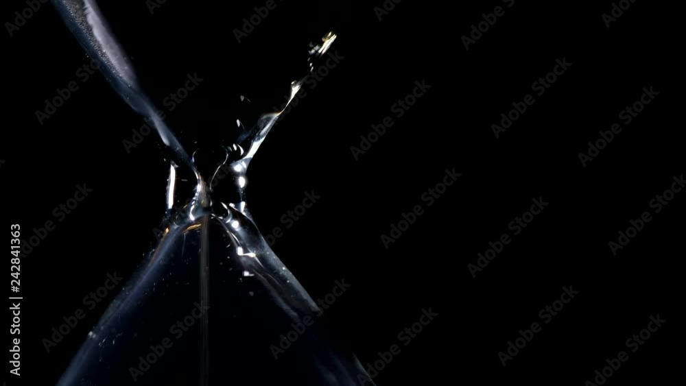 The sand flow in the hourglass with black background and lateral light backlight in lateral composition and possible endless loop