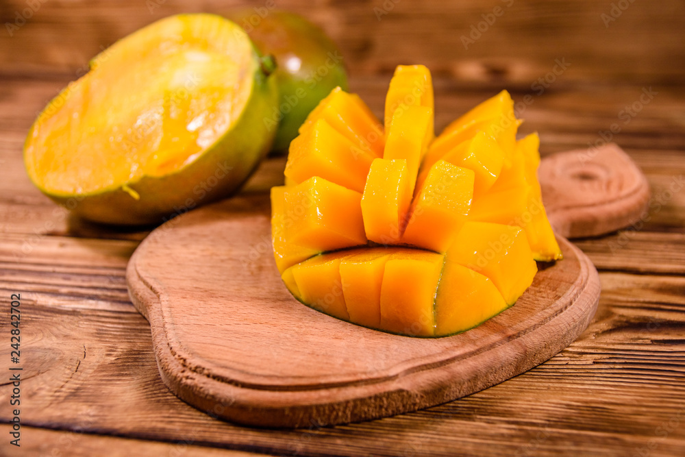 Cutting board with chopped mango fruit on a wooden table Cutting board with chopped mango fruit on a wooden table