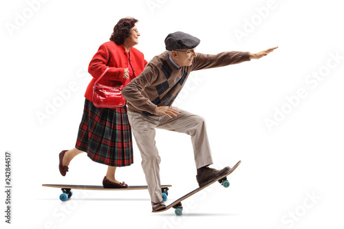 Elderly lady and an elderly man riding a longboard