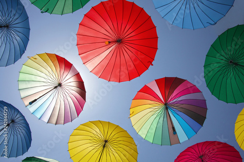 Collection of multi colored umbrellas hanging up.