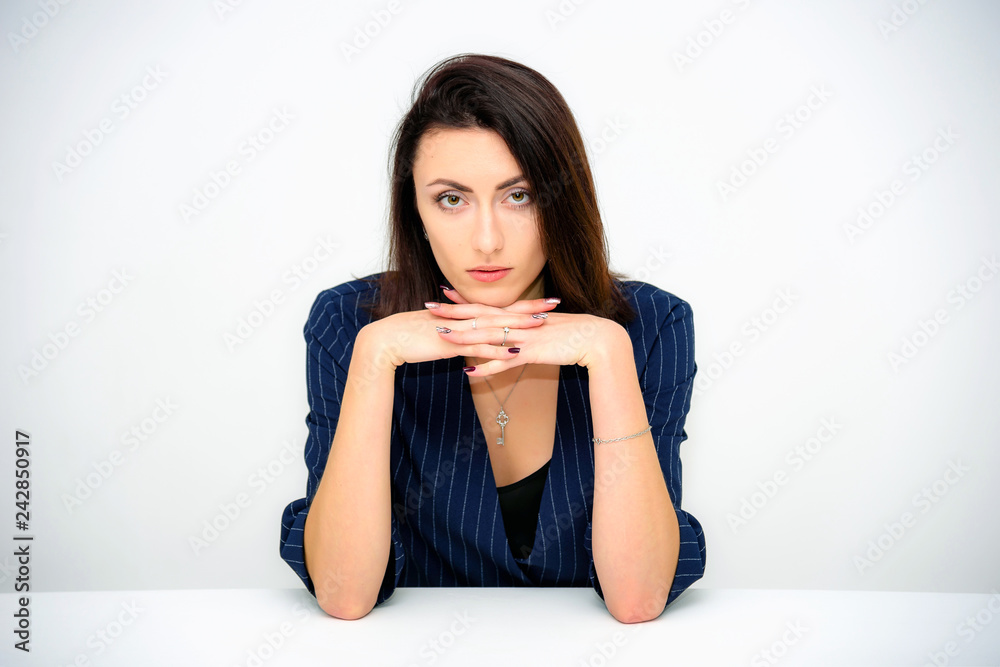 Concept beautiful business woman secretary manager on a white background sitting at a table in various poses right in front of the camera. She works with documents with different emotions. Concept beautiful business woman secretary manager on a white background sitting at a table in various poses right in front of the camera. She works with documents with different emotions.
