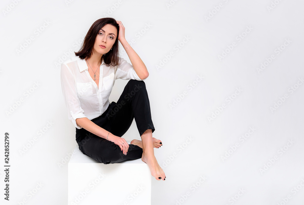 Concept portrait of a girl sitting on a white background in a business suit in different poses with different emotions. It in the middle of the frame, next to the white cubes, next is another cube. Concept portrait of a girl sitting on a white background in a business suit in different poses with different emotions. It in the middle of the frame, next to the white cubes, next is another cube.