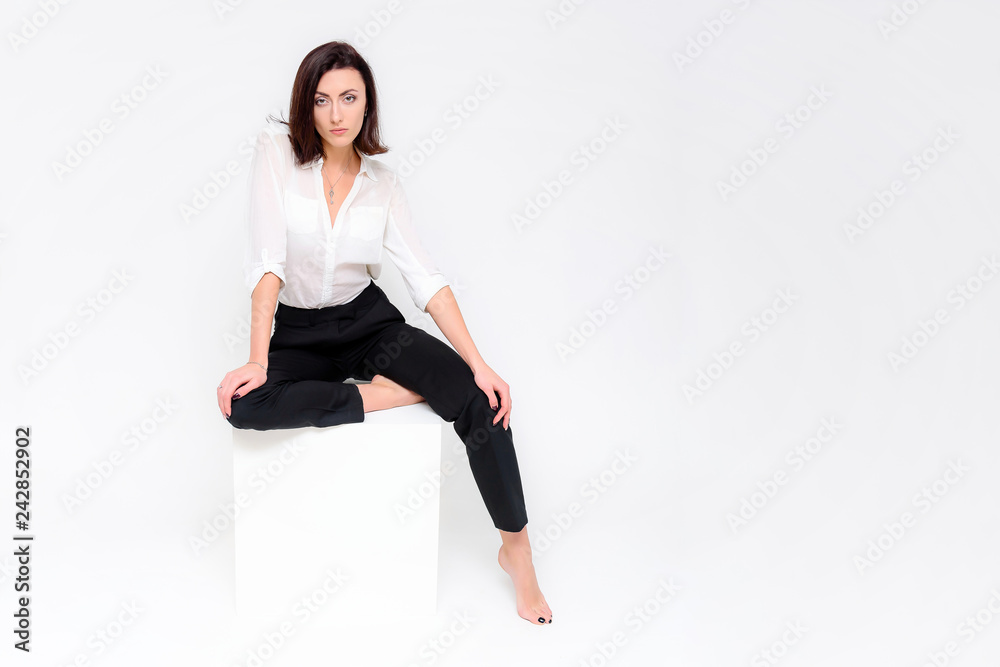 Concept portrait of a girl sitting on a white background in a business suit in different poses with different emotions. It in the middle of the frame, next to the white cubes, next is another cube. Concept portrait of a girl sitting on a white background in a business suit in different poses with different emotions. It in the middle of the frame, next to the white cubes, next is another cube.