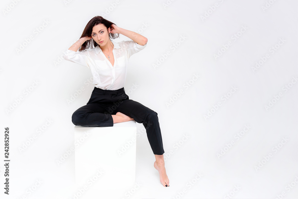 Concept portrait of a girl sitting on a white background in a business suit in different poses with different emotions. It in the middle of the frame, next to the white cubes, next is another cube. Concept portrait of a girl sitting on a white background in a business suit in different poses with different emotions. It in the middle of the frame, next to the white cubes, next is another cube.