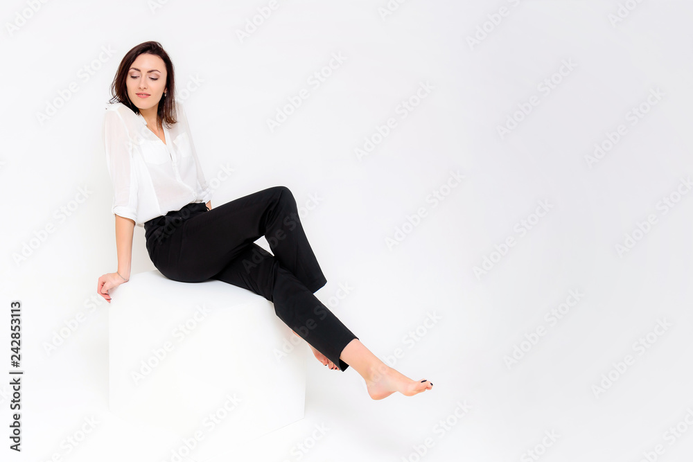 Concept portrait of a girl sitting on a white background in a business suit in different poses with different emotions. It in the middle of the frame, next to the white cubes, next is another cube. Concept portrait of a girl sitting on a white background in a business suit in different poses with different emotions. It in the middle of the frame, next to the white cubes, next is another cube.
