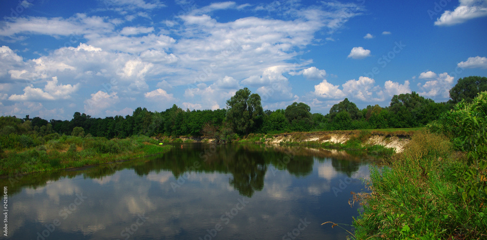 Summer landscape with a flat river and clouds in the blue sky. Ukraine, River Seim