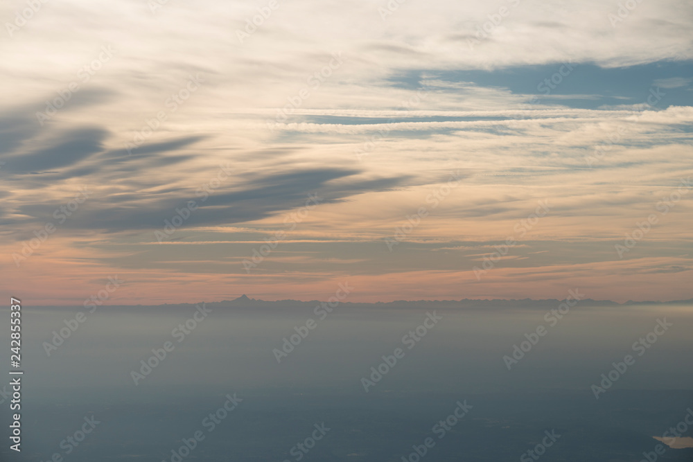 Aerial view at sunset or sunrise of a fog covered plain with mountain in the background