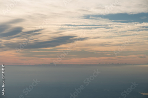 Aerial view at sunset or sunrise of a fog covered plain with mountain in the background