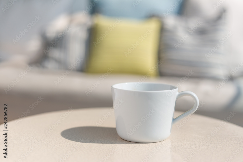 White ceramic coffee cup on white ceramic table, outdoor on sunny day White ceramic coffee cup on white ceramic table, outdoor on sunny day
