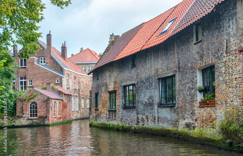 Bruges, Belgium. Medieval ancient houses made of old bricks at water channel with boats in old town. Bruges, Belgium. Medieval ancient houses made of old bricks at water channel with boats in old town.