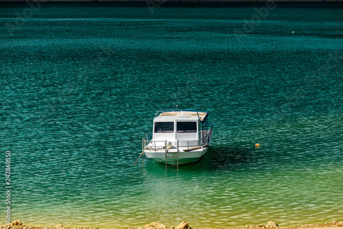 Motorboat moored on the turquoise lake surface. © Kozioł Kamila