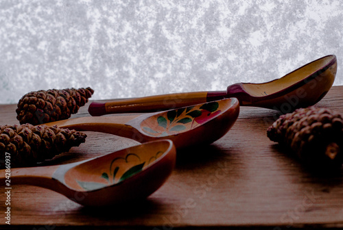Wood spoon with three cones on wood table near the window