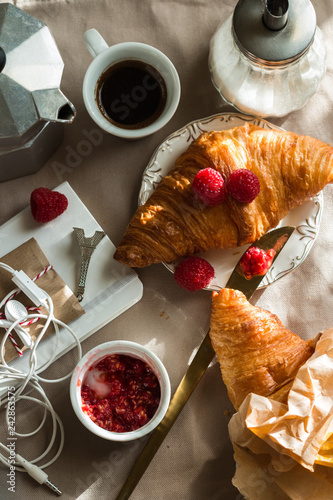 Kitchen table with french breakfast set. Freshly baked croissant, raspberry jam and coffee, blocnote, berries. Top view. photo