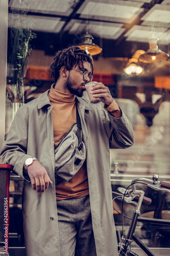 Kind bearded male person drinking hot chocolate