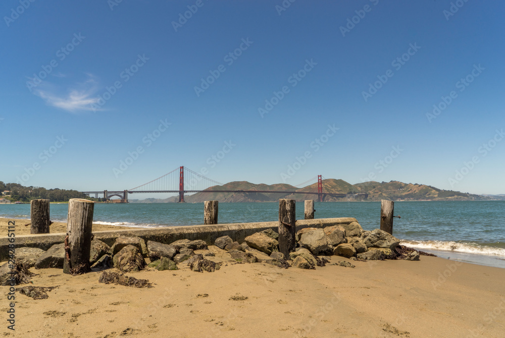 ramins of old wooden pier on the beach with Golden Gate bridge in background