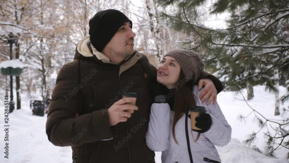 Young loving couple walking in winter city Park. Lovers talking, laughing, kissing and drinking of coffee. Young loving couple walking in winter city Park. Lovers talking, laughing, kissing and drinking of coffee.
