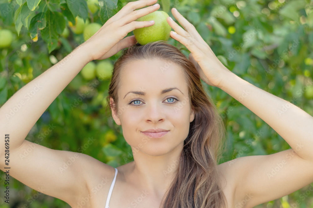 Summertime in garden. Young woman is holding a juicy green apple in her hand. Summertime in garden. Young woman is holding a juicy green apple in her hand.