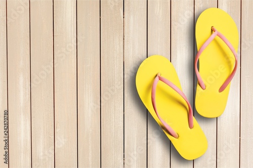 Yellow rubber sandals flip flops on wooden