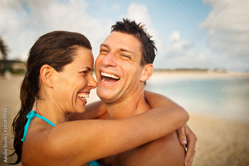 Laughing mid-adult couple hugging on a sandy beach. Laughing mid-adult couple hugging on a sandy beach.