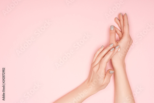 partial view of woman applying hand cream isolated on pink