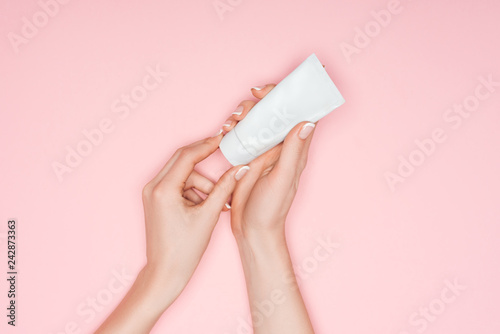 cropped view of female hands with hand cream isolated on pink photo