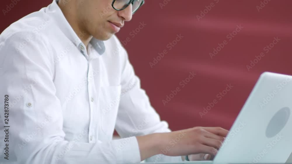 Tilt up shot of concentrated young Asian businessman typing on laptop computer keyboard while working in office Tilt up shot of concentrated young Asian businessman typing on laptop computer keyboard while working in office