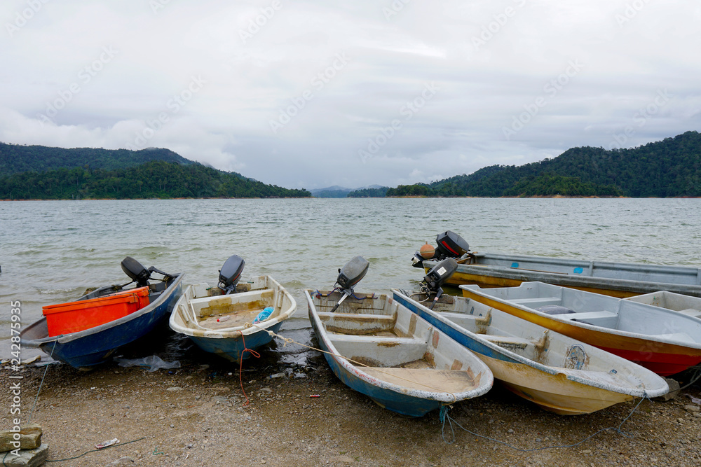 Old and used fishing boat by the side of the lake - Asian Style - Small fiberglass boat use for fishing or transportation around the lake is grounded on the gravel bed - Image Old and used fishing boat by the side of the lake - Asian Style - Small fiberglass boat use for fishing or transportation around the lake is grounded on the gravel bed - Image