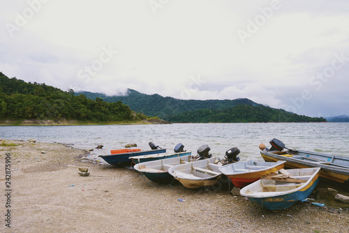 Old and used fishing boat by the side of the lake - Asian Style - Small fiberglass boat use for fishing or transportation around the lake is grounded on the gravel bed - Image