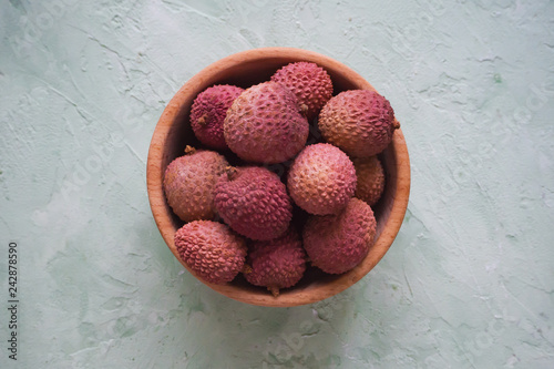 Litchi in a wooden bowl on a grey table.