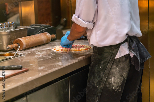 Chef in uniform making Italian pizza in the kitchen restaurant