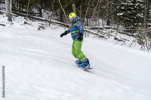 Snowboarder jumping in the mountains on a forest background