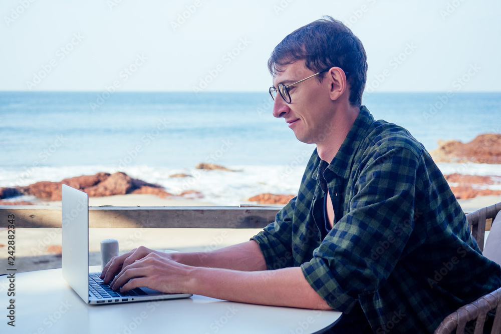 Funny business man geek using laptop on tropical vacation