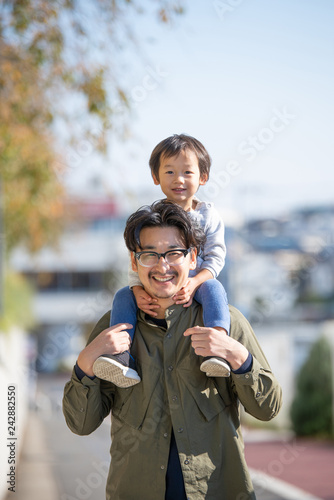 Portrait of smiling father carrying son on shoulder photo