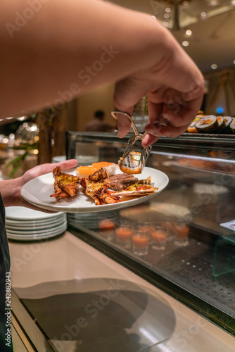 Vertical photo of young man choosing food in the hotel buffet